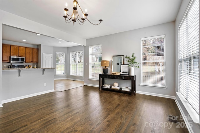 living room with dark hardwood / wood-style floors, a wealth of natural light, and a chandelier