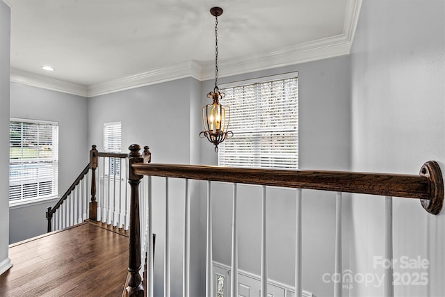 staircase featuring hardwood / wood-style floors, a chandelier, and ornamental molding