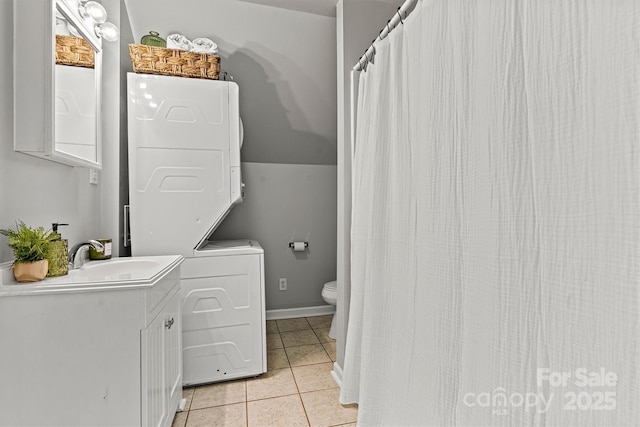 bathroom with stacked washing maching and dryer, toilet, tile patterned floors, and vanity