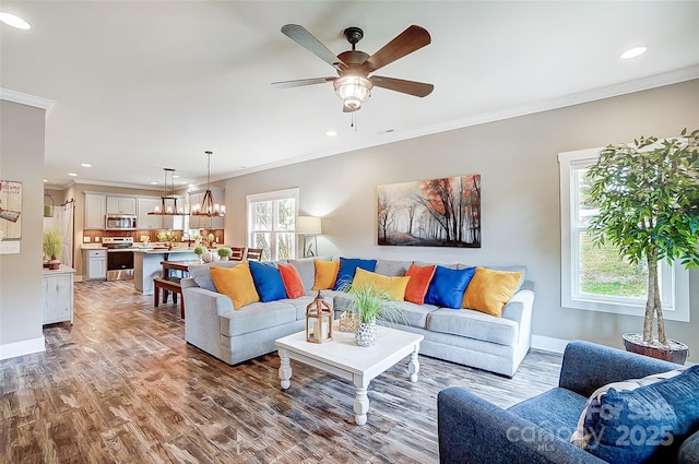 living room with hardwood / wood-style floors, ceiling fan with notable chandelier, and ornamental molding