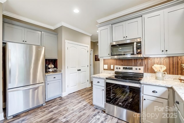 kitchen featuring stainless steel appliances, tasteful backsplash, light stone counters, gray cabinets, and ornamental molding