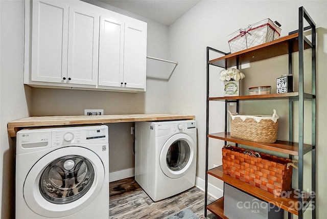 laundry room with washing machine and clothes dryer, cabinets, and light hardwood / wood-style floors