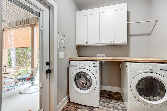 clothes washing area featuring cabinets, dark wood-type flooring, and washing machine and clothes dryer