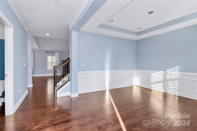 unfurnished room featuring a tray ceiling, crown molding, and dark hardwood / wood-style floors