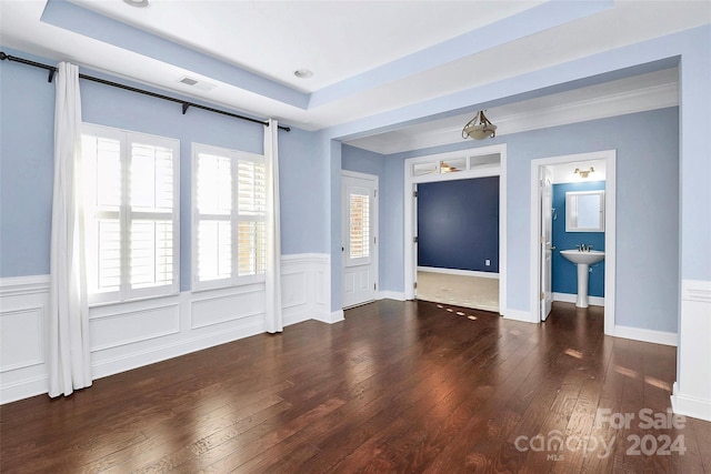 spare room with dark hardwood / wood-style floors and a raised ceiling