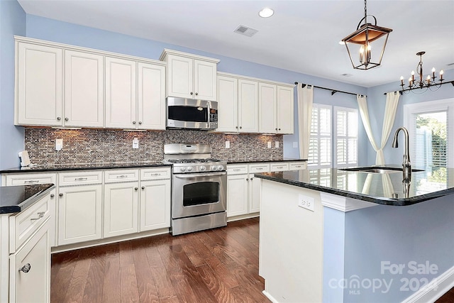 kitchen with sink, hanging light fixtures, dark wood-type flooring, a kitchen island with sink, and appliances with stainless steel finishes