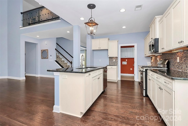 kitchen featuring sink, hanging light fixtures, dark hardwood / wood-style floors, an island with sink, and appliances with stainless steel finishes