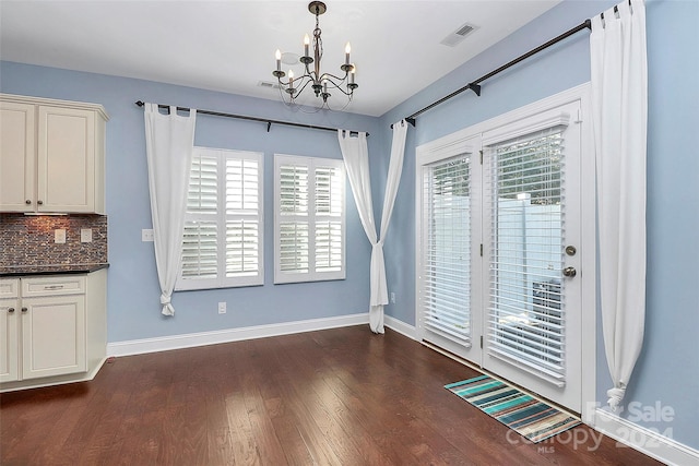 unfurnished dining area with dark hardwood / wood-style flooring and an inviting chandelier