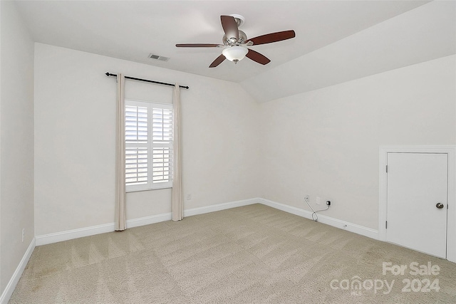 carpeted spare room featuring ceiling fan and vaulted ceiling