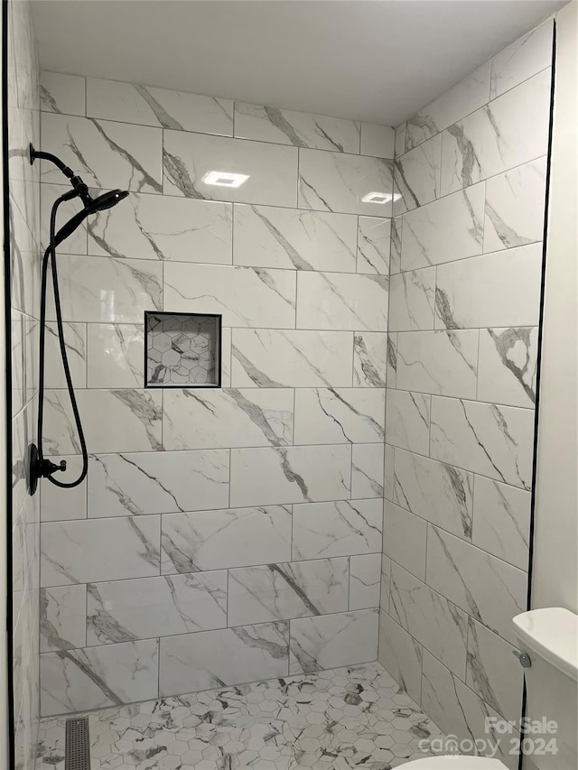 bathroom featuring tiled shower and toilet