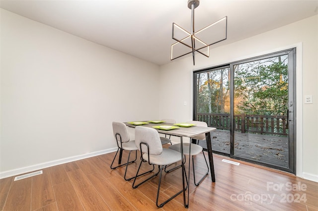 dining space with light hardwood / wood-style floors and an inviting chandelier