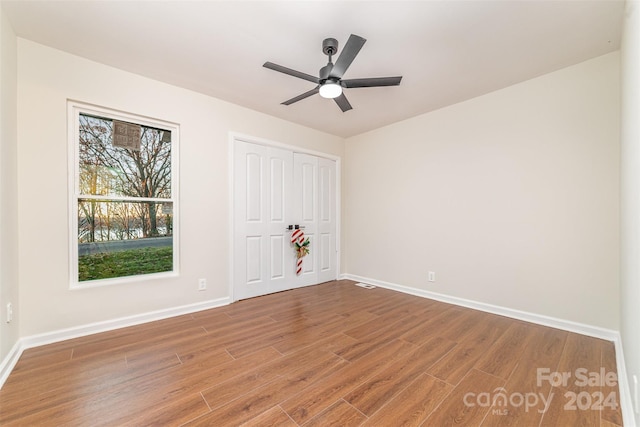 unfurnished bedroom featuring hardwood / wood-style floors, a closet, and ceiling fan