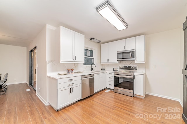 kitchen featuring light wood-type flooring, white cabinetry, sink, and appliances with stainless steel finishes