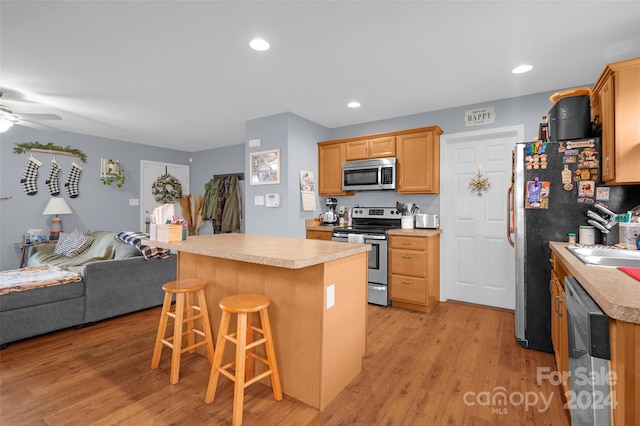 kitchen with a kitchen breakfast bar, a kitchen island, stainless steel appliances, and light wood-type flooring