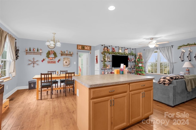 kitchen featuring ceiling fan with notable chandelier, a kitchen island, and light wood-type flooring