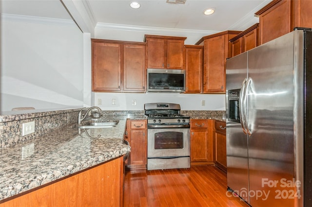 kitchen with sink, stainless steel appliances, light stone counters, crown molding, and light hardwood / wood-style floors