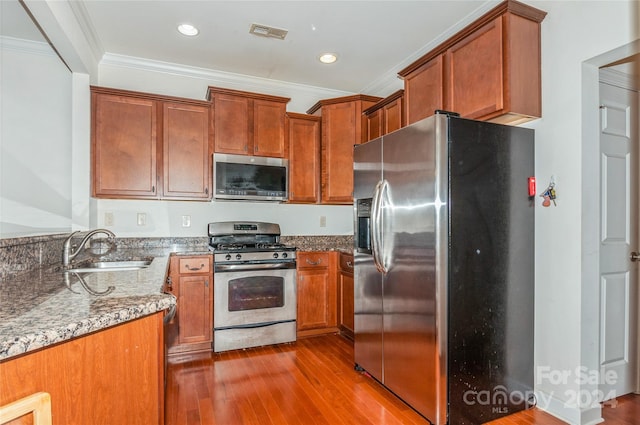 kitchen with hardwood / wood-style flooring, sink, light stone counters, and appliances with stainless steel finishes