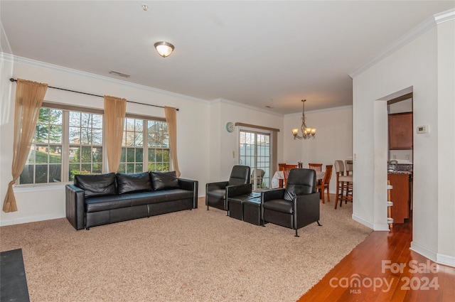 living room featuring wood-type flooring, an inviting chandelier, and crown molding