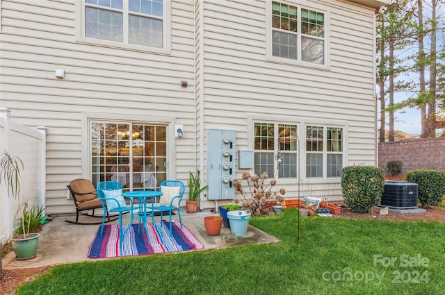 rear view of house featuring cooling unit, a yard, and a patio