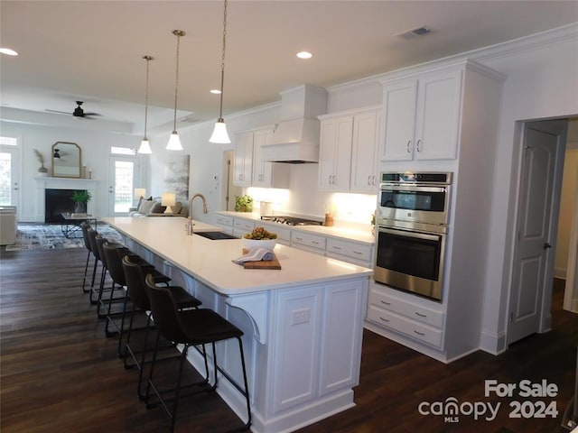 kitchen with white cabinetry, ceiling fan, sink, a spacious island, and custom range hood