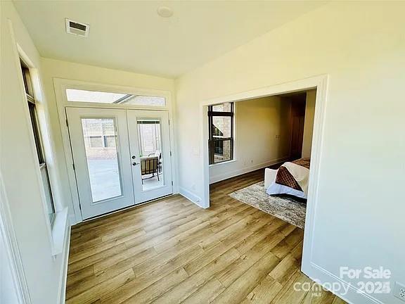 entryway featuring light wood-style floors, french doors, visible vents, and baseboards