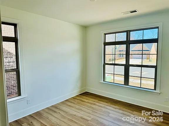 unfurnished room featuring baseboards, visible vents, and wood finished floors