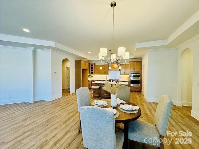 dining space with light wood finished floors, baseboards, arched walkways, a chandelier, and recessed lighting