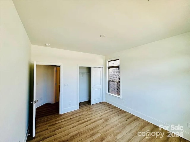 unfurnished bedroom featuring a closet, baseboards, and light wood finished floors