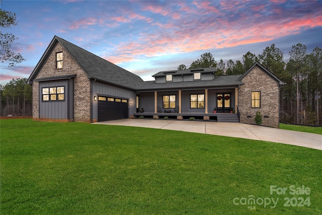 view of front of property featuring a porch, a garage, and a lawn