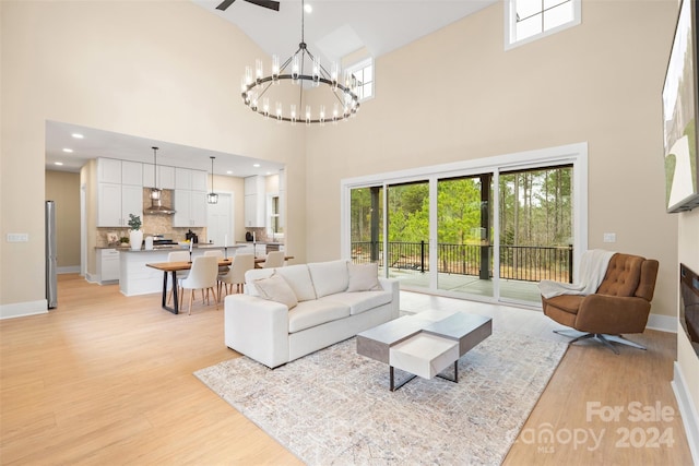 living room with light hardwood / wood-style flooring, a high ceiling, and a notable chandelier