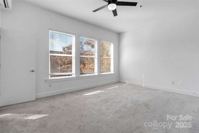 carpeted spare room with a wall unit AC, a wealth of natural light, and ceiling fan