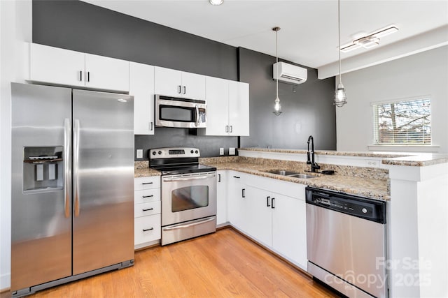 kitchen with hanging light fixtures, white cabinetry, stainless steel appliances, and a wall unit AC