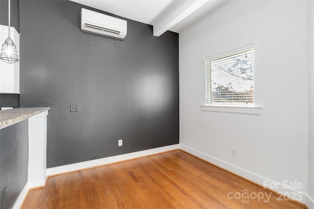 unfurnished dining area featuring beamed ceiling, light hardwood / wood-style floors, and an AC wall unit