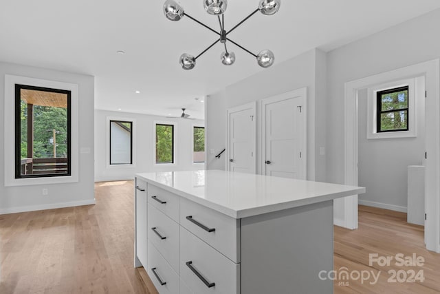 walk in closet featuring ceiling fan with notable chandelier and light wood-type flooring