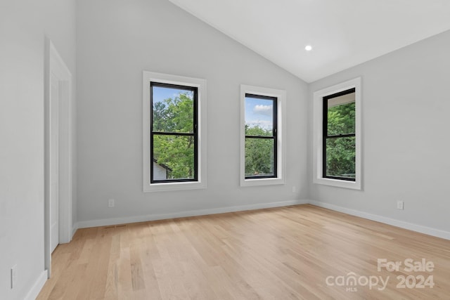 unfurnished room with light hardwood / wood-style floors and lofted ceiling