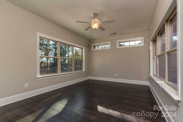 spare room featuring plenty of natural light, ceiling fan, and dark hardwood / wood-style flooring