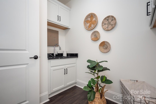 interior space with dark wood-style floors, a sink, and baseboards