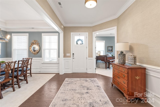 foyer entrance featuring dark hardwood / wood-style flooring, crown molding, and an inviting chandelier