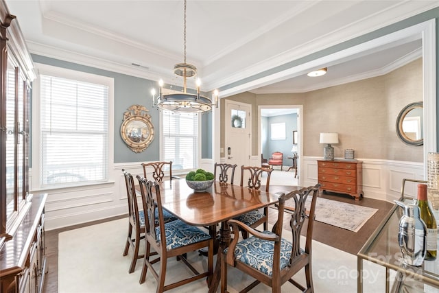 dining space with hardwood / wood-style floors, ornamental molding, and an inviting chandelier