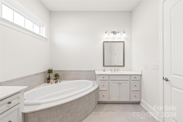 bathroom featuring tile patterned flooring, vanity, and tiled bath