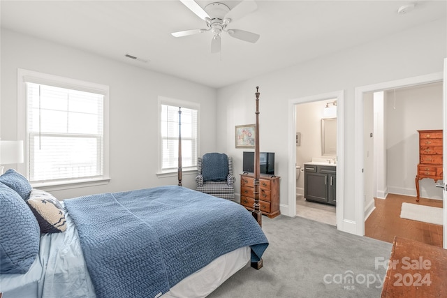 bedroom featuring ensuite bath, ceiling fan, sink, and light carpet