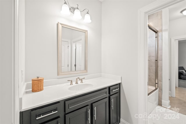 bathroom featuring tile patterned flooring, vanity, and combined bath / shower with glass door