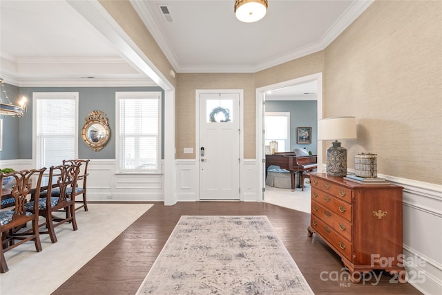 entryway with crown molding, a wainscoted wall, and visible vents