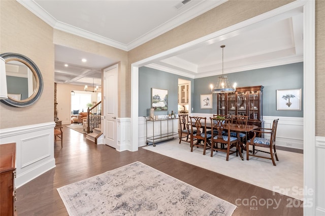 dining space with an inviting chandelier, crown molding, wood finished floors, and visible vents