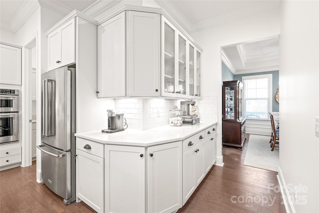 kitchen with white cabinets, wood finished floors, ornamental molding, and stainless steel appliances
