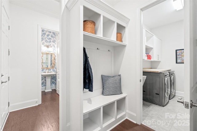 mudroom featuring wood finished floors, washing machine and clothes dryer, baseboards, and a sink