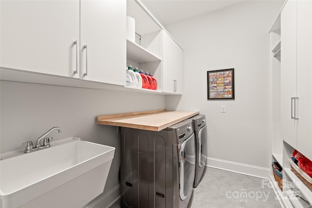 laundry area with cabinet space, independent washer and dryer, baseboards, and a sink