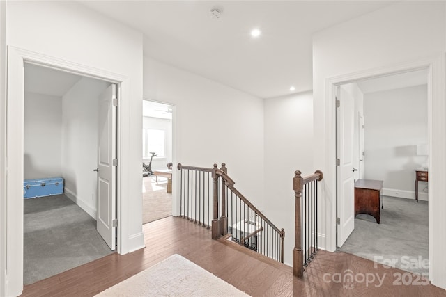 corridor featuring recessed lighting, wood finished floors, an upstairs landing, baseboards, and carpet flooring