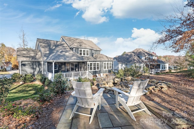 back of property featuring a patio area, a sunroom, and roof with shingles