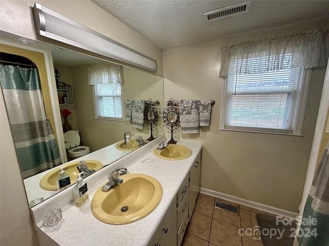 bathroom with tile patterned floors, plenty of natural light, toilet, and vanity